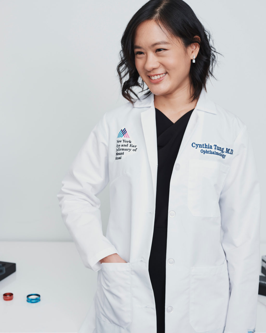 Dr. Cynthia Tung wears a black skirt, black top and her white lab coat. 